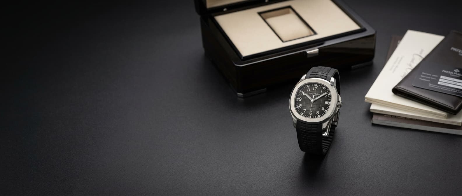 Luxury watch with box and papers on dark surface